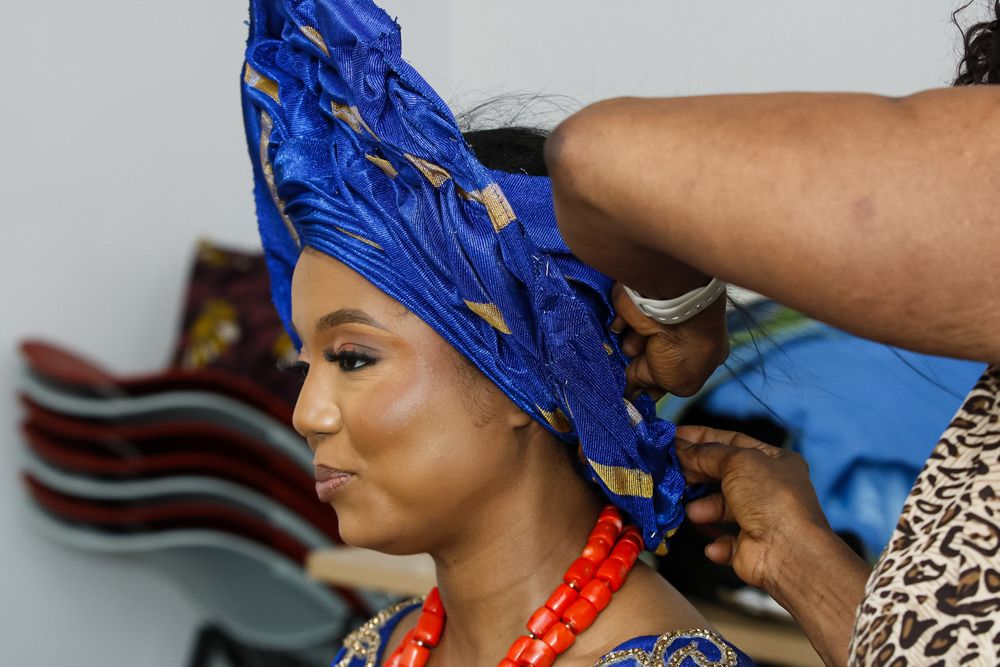 Two people wearing vibrant blue and orange traditional African attire share a joyful moment at a celebration.
