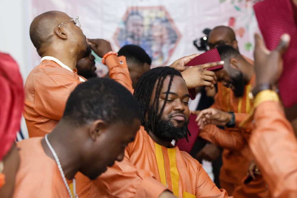 Wedding celebration with guests in vibrant orange and traditional formal attire.