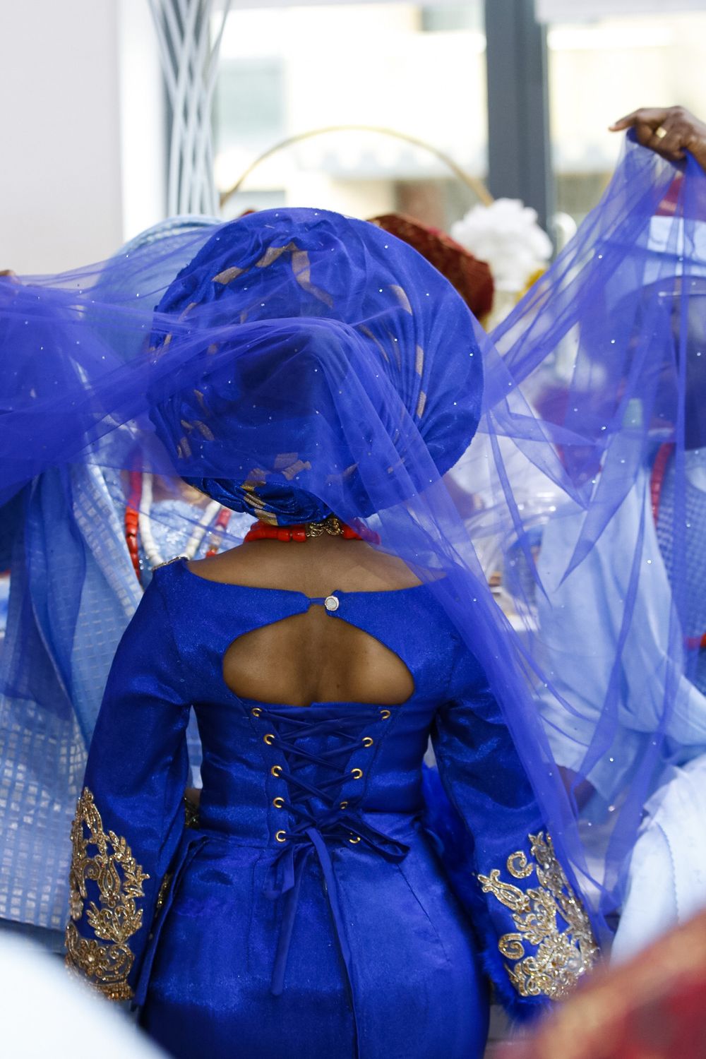 A royal blue traditional dress with gold embroidery details is displayed from the back.
