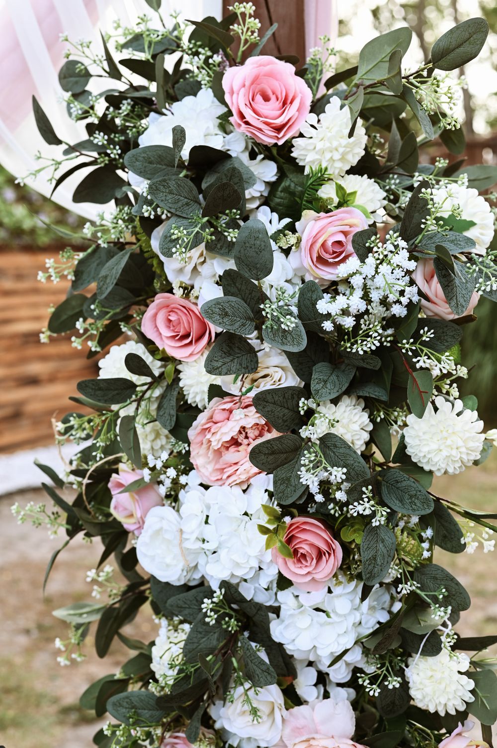 Elegant floral arrangement with pink roses, white flowers and greenery for wedding decoration.