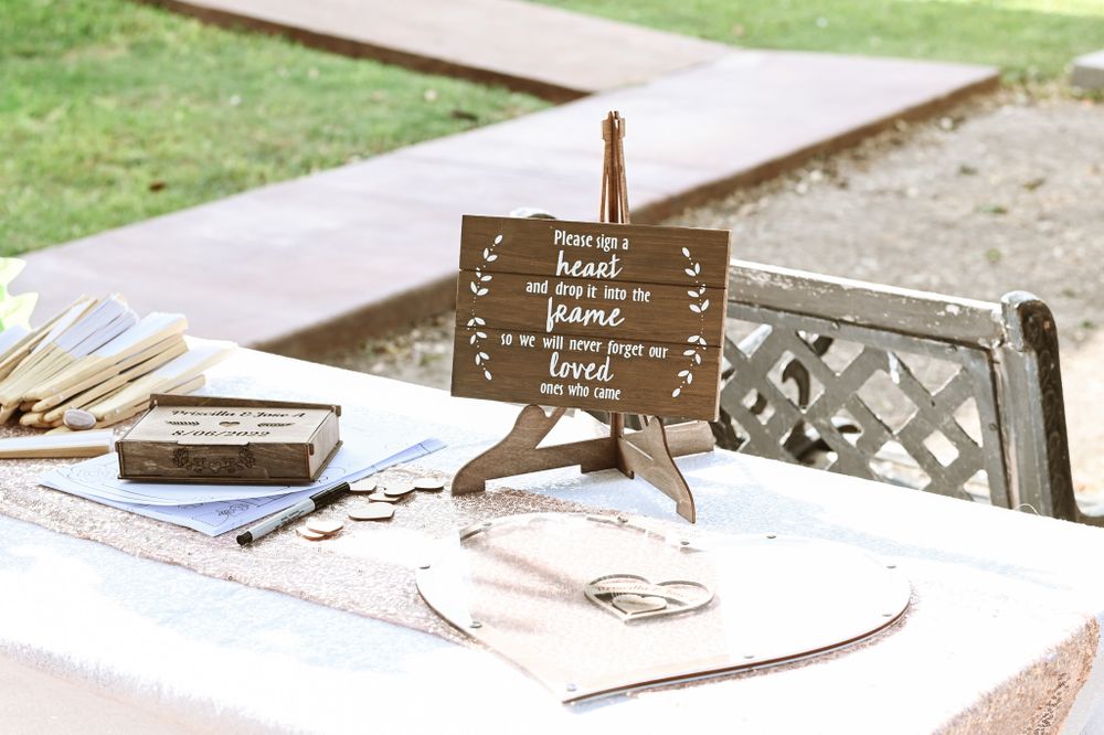 Vintage wooden wedding guestbook sign on white tablecloth with decorative elements.