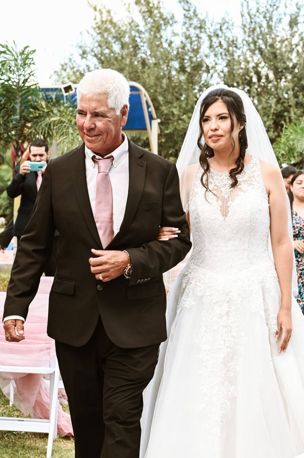 Wedding ceremony processional in an outdoor garden setting.