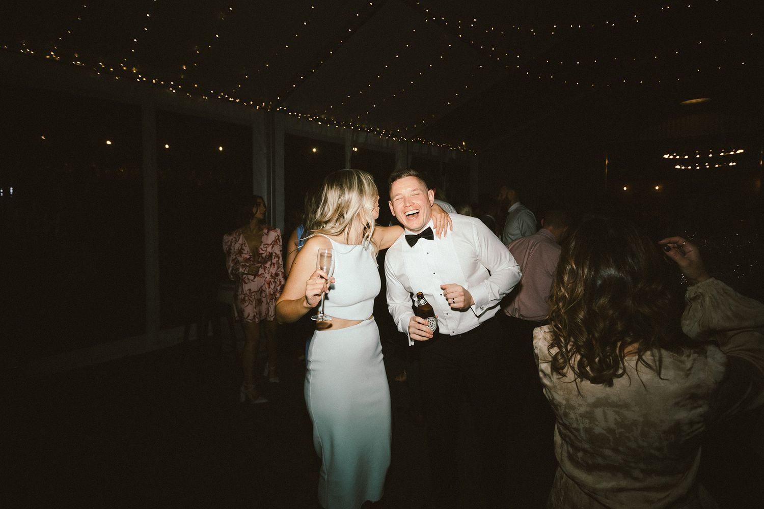 Wedding celebration dance floor with guests enjoying themselves under sparkly overhead lights.