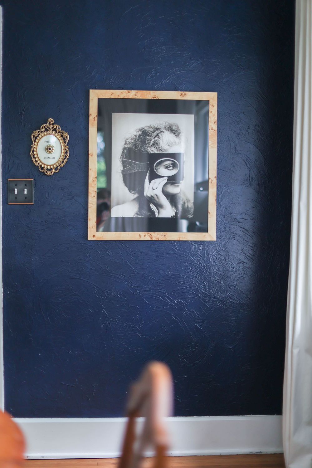 Navy blue accent wall decorated with framed artwork and mirrors in a modern home setting.