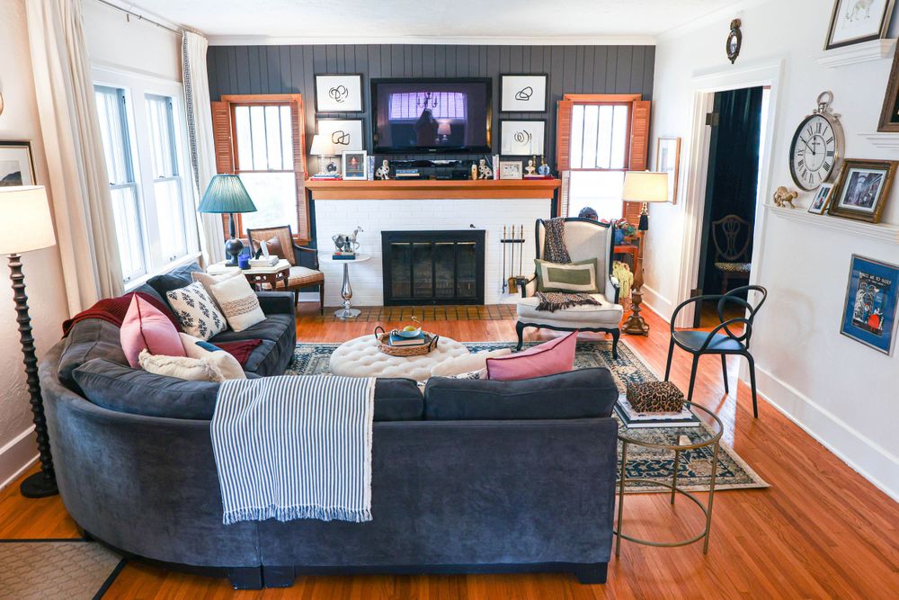 Panoramic view of modern living space with navy sofa and hardwood flooring.