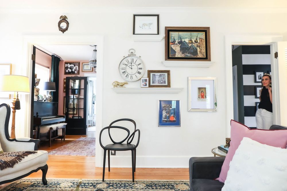 White living room wall decorated with framed artwork and modern black accent chairs.