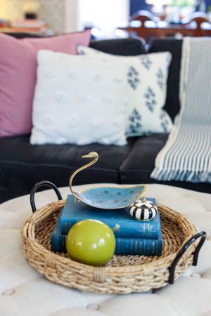 Woven basket tray with decorative green sphere and blue book on display.