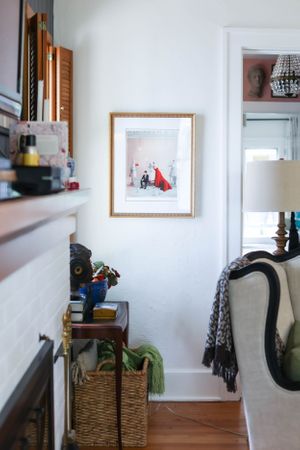Hallway view with white walls, framed artwork, and woven storage basket.