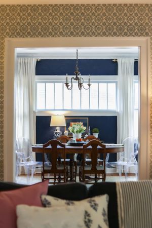 Dining area with damask wallpaper, navy accent wall, and traditional wood furniture.