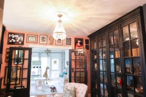 Spacious room with pink walls features dark built-in cabinets and framed artwork.
