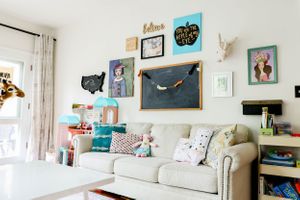 White room with colorful artwork and decor displayed on walls and shelves.
