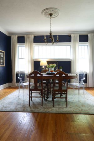 Elegant dining room with navy walls, hardwood floors and traditional wooden furniture.