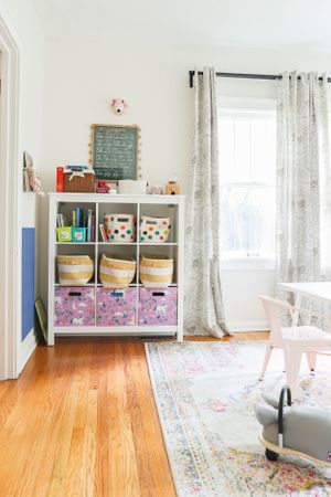 Spacious room with hardwood floors, white curtains, and organized storage solutions.