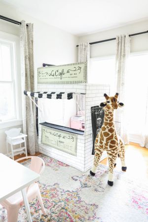 Playroom with white walls, floral rug, and decorative giraffe plush.