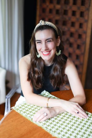 Person crafting with green and white patterned fabric on wooden table.