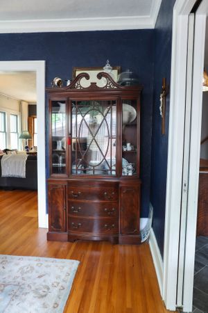 Traditional wooden furniture and hardwood floors in room with navy blue walls.
