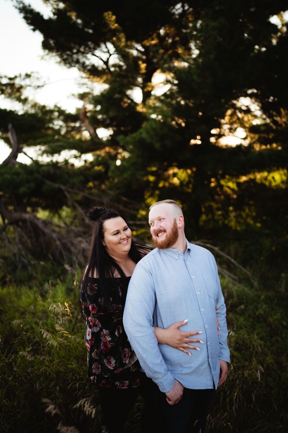 A romantic outdoor photoshoot with a couple in complementary outfits laughing together.