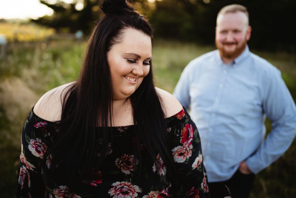 A couple sharing a joyful moment outdoors with a floral off-shoulder dress and light blue shirt.