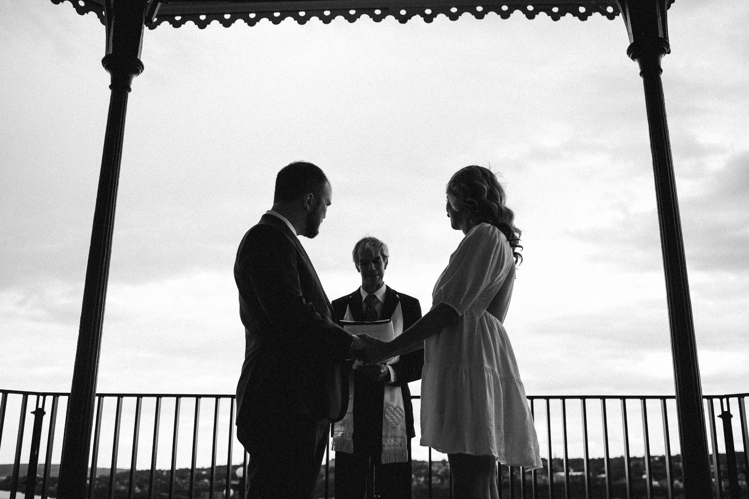 A silhouetted wedding ceremony under a gazebo at dusk.
