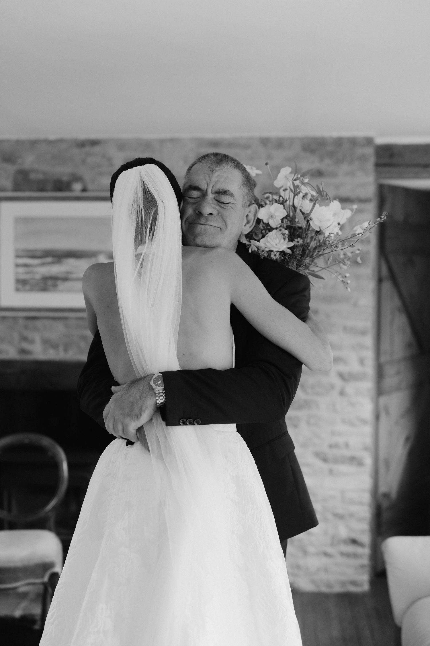 father of bride hugging bride after seeing her in her wedding dress for the first time before leaving for wedding ceremony in Oxfordshire
