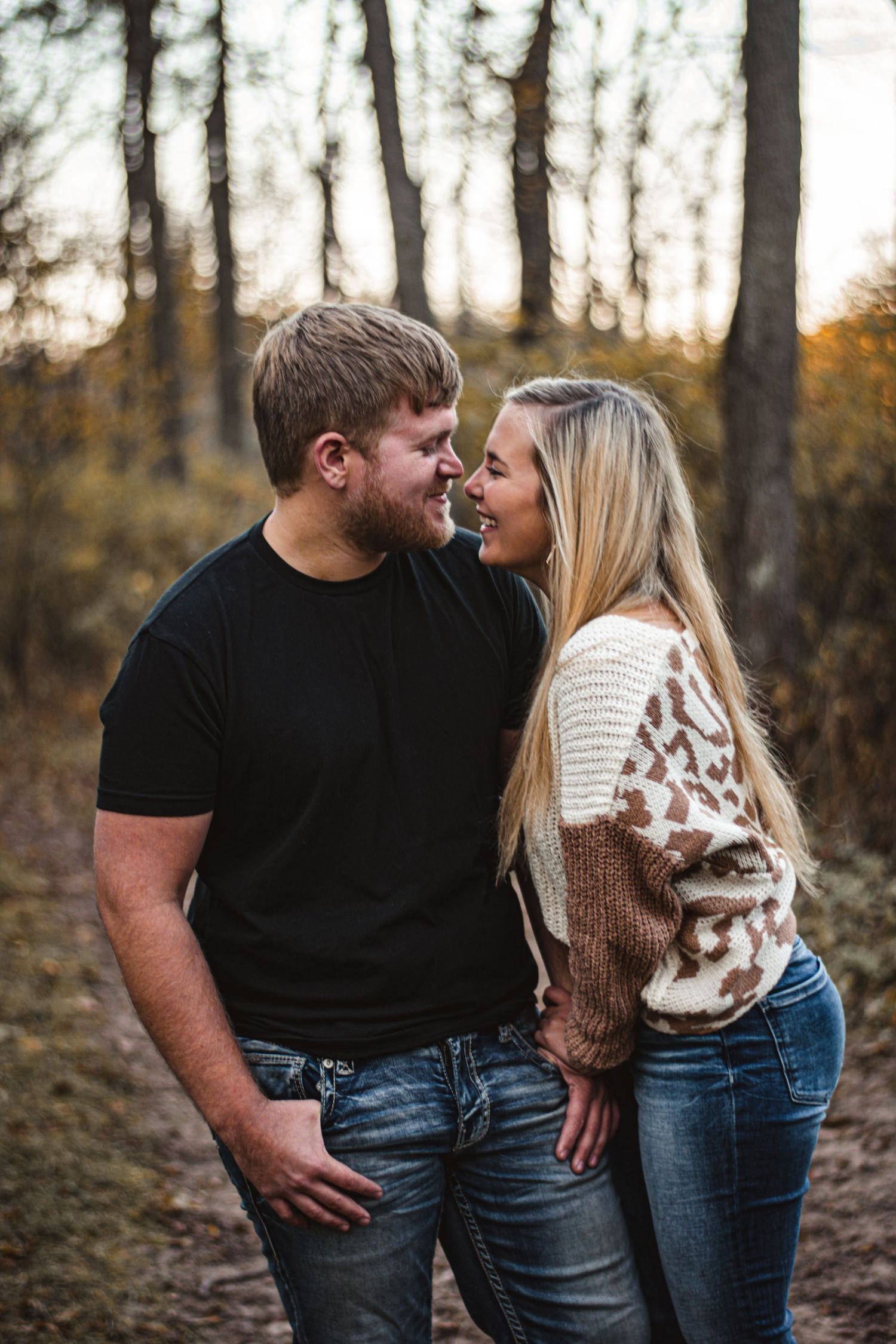 Casual couple shares intimate moment during forest engagement photoshoot.