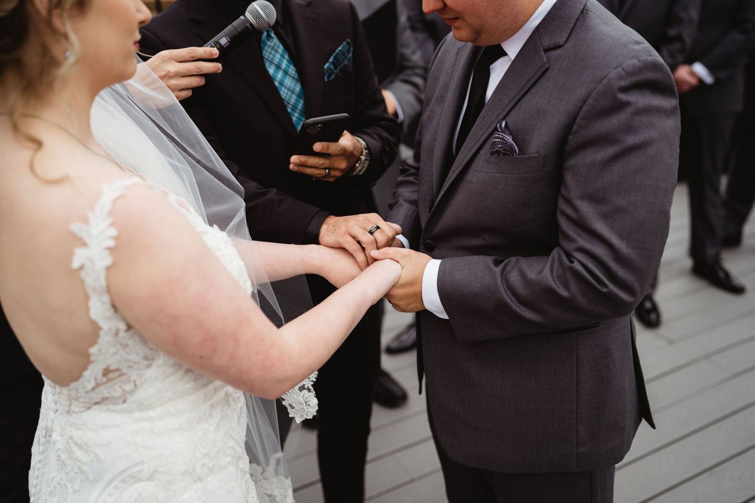 Close-up of ring exchange during wedding ceremony on outdoor deck.