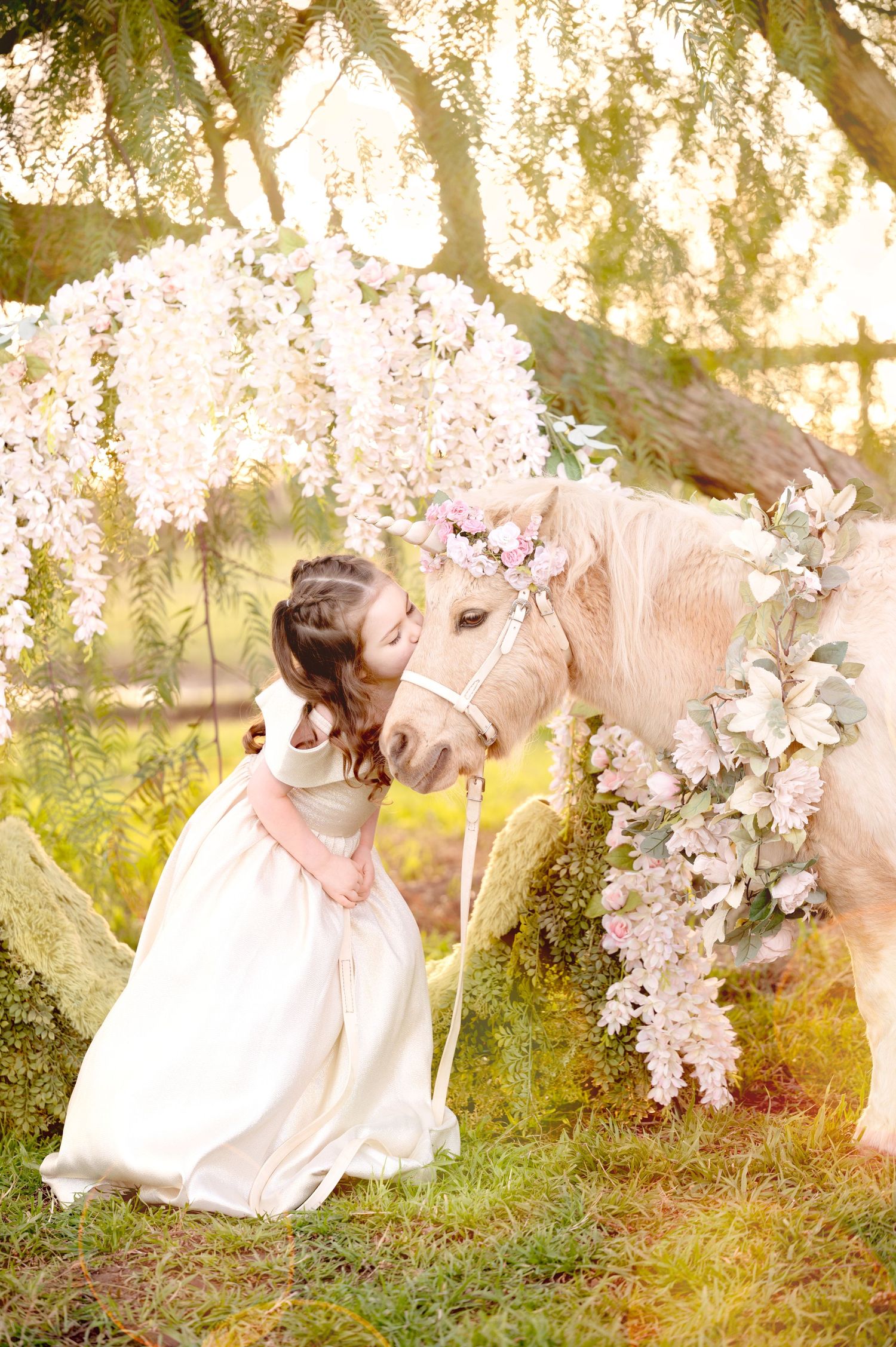 Gentle moment with a cream-colored pony decorated with cherry blossoms in a magical garden setting.