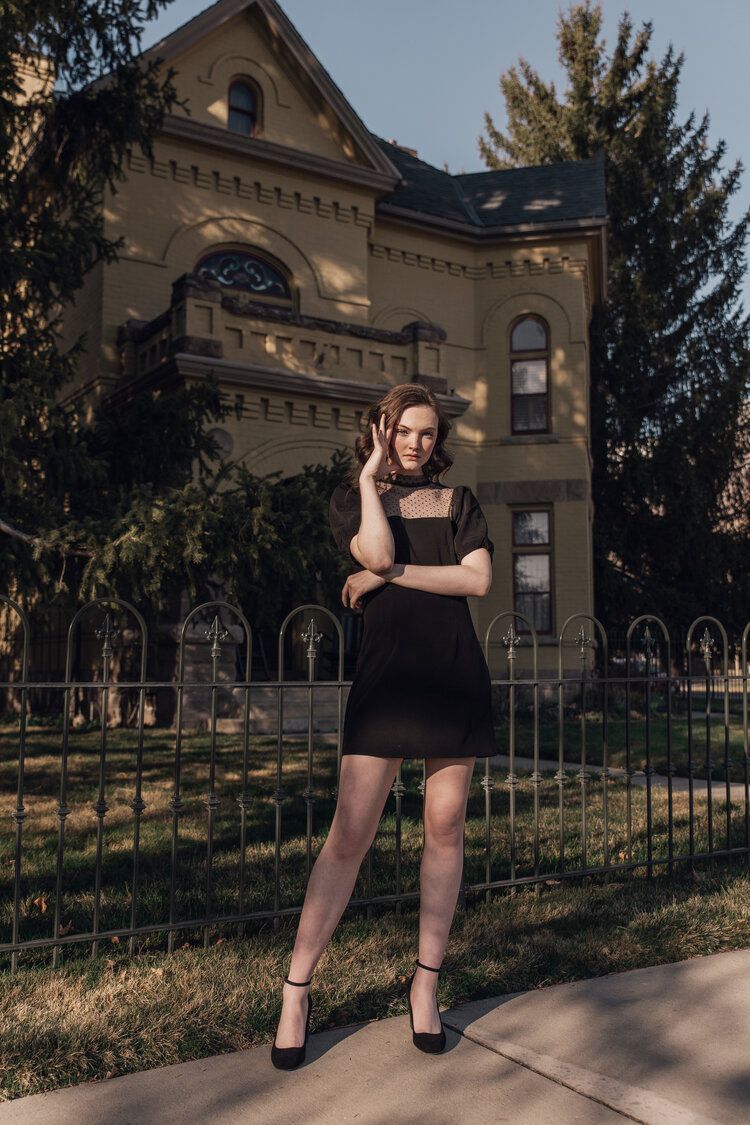 Model standing in front of historic home with black mini dress in moody lighting, Atlanta editorial portrait and fashion photographer