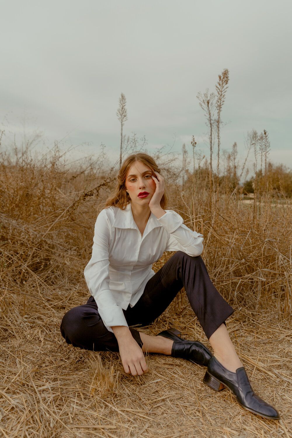 Editorial model sitting in field with white shirt and black trousers, Atlanta editorial portrait and fashion photographer
