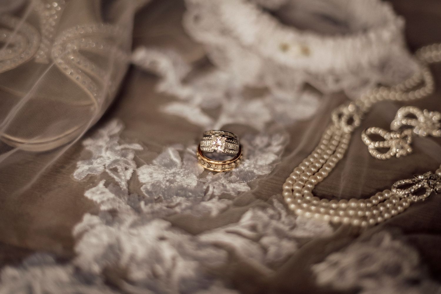 Wedding accessories including pearl necklace, tiara and delicate lace details arranged on neutral background.