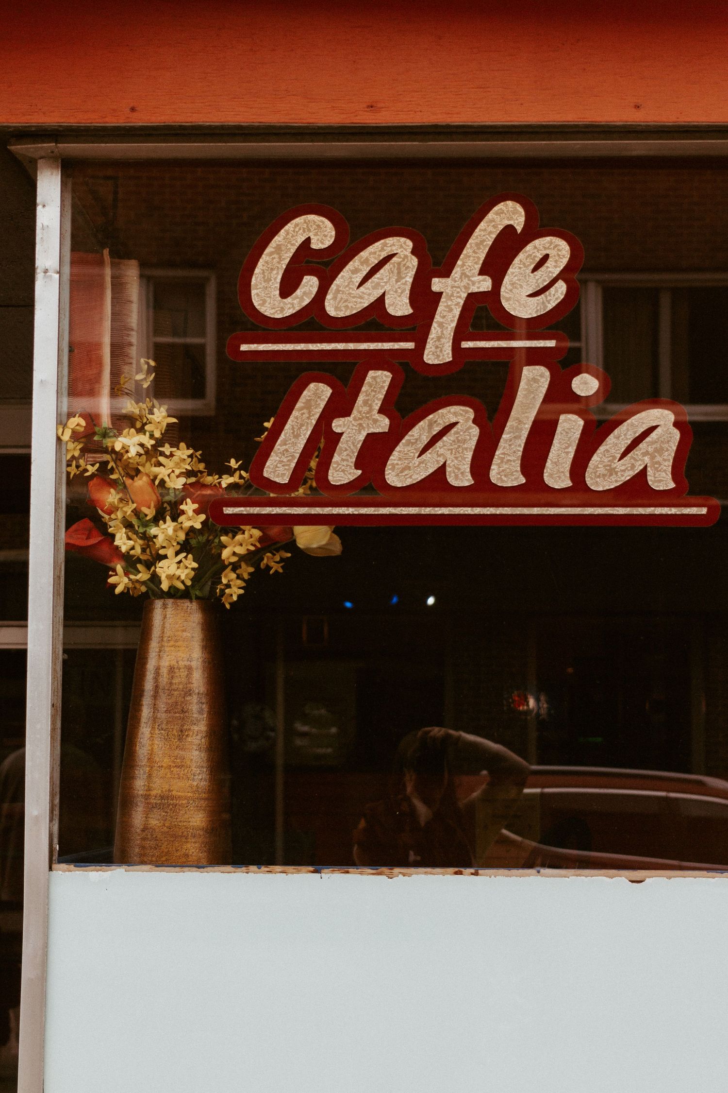 Vintage-style Cafe Italia storefront sign with red lettering against dark background.