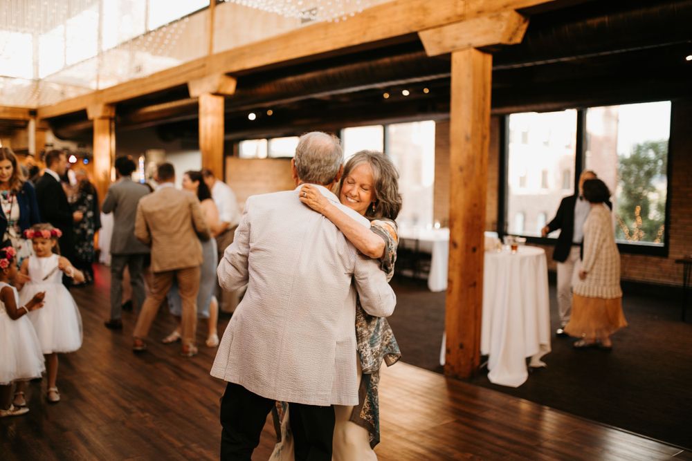 Older couple shares a warm embrace while dancing together on the wedding reception dance floor.