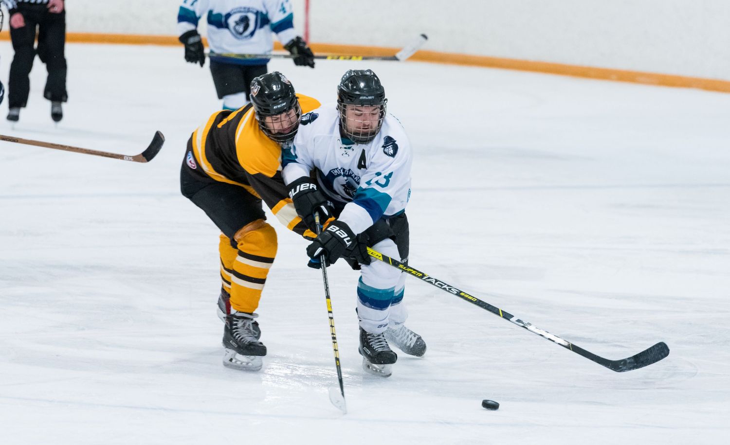 Hockey players from opposing teams compete for control of the puck during an ice hockey match.
