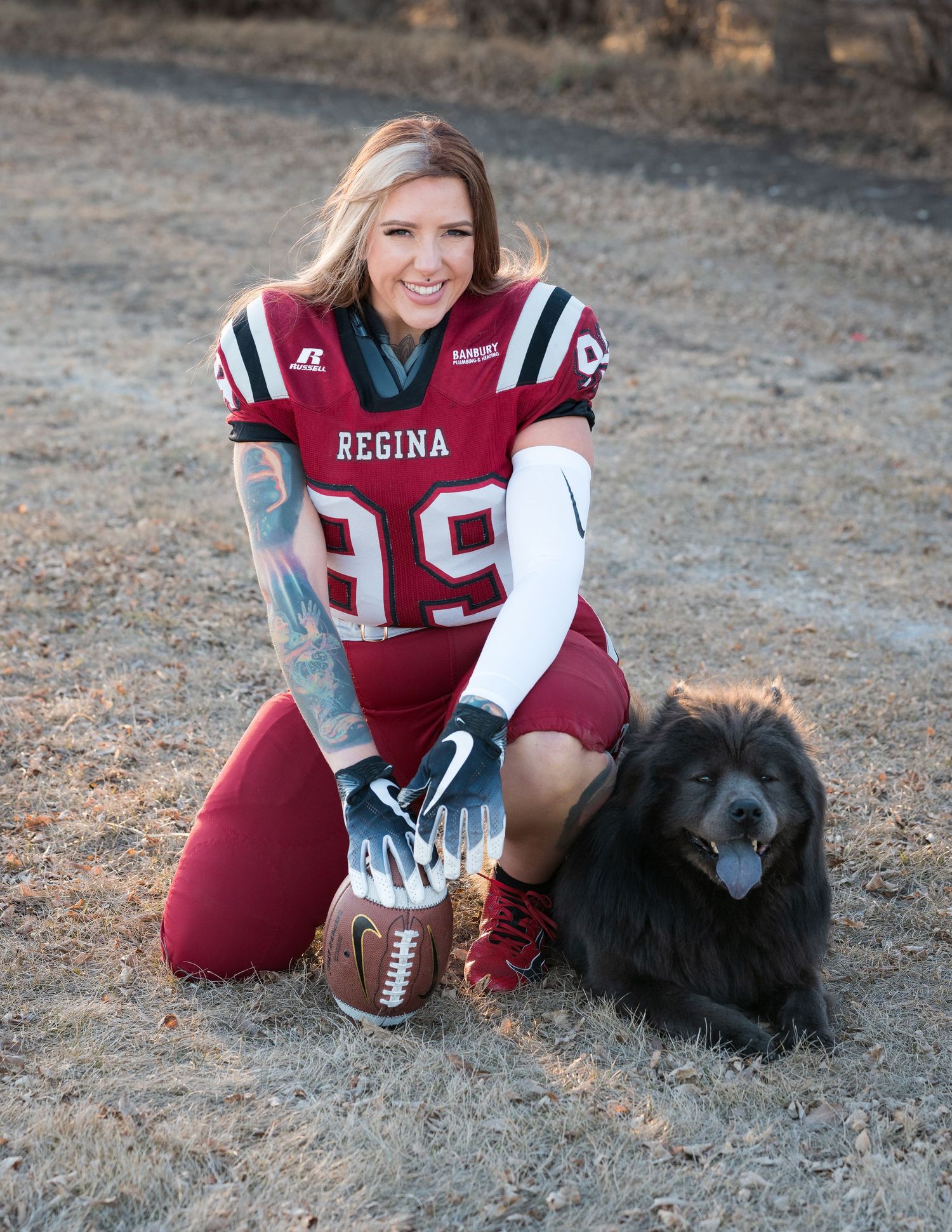 Regina football player with black dog poses with football in outdoor setting.