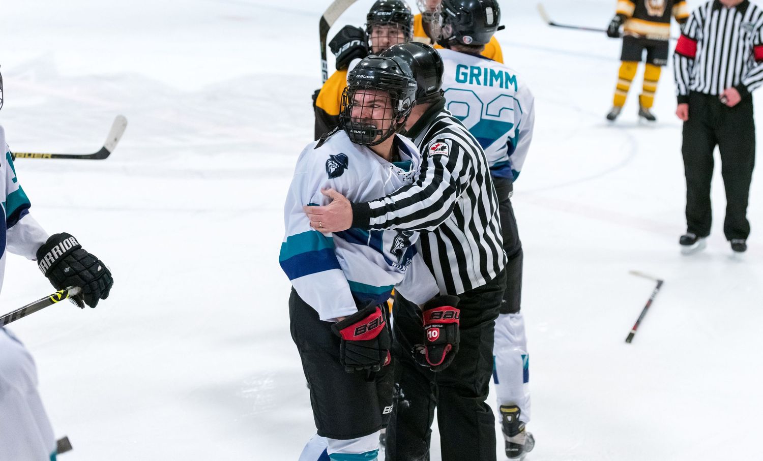 Referees separate hockey players during an on-ice confrontation as equipment lays scattered.