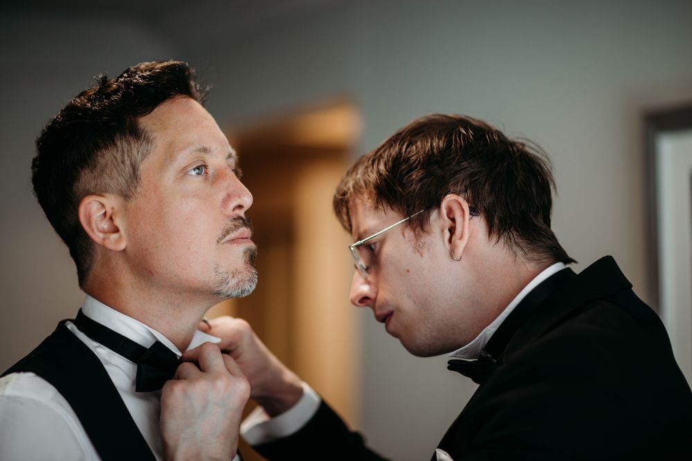 Two people in formal wear share a close moment while getting ready.