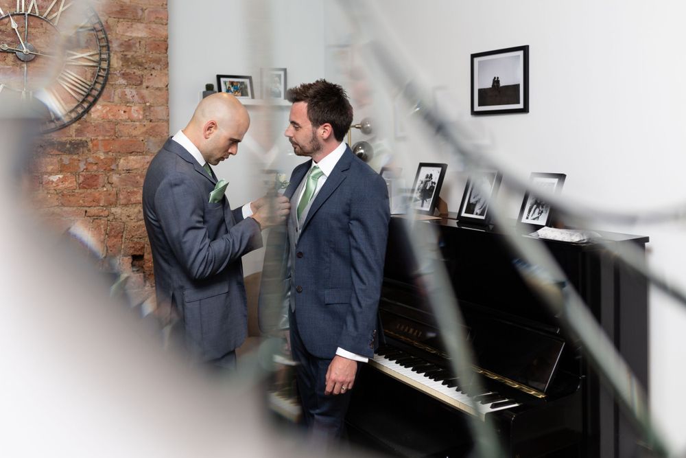 Two people in suits having an intimate conversation near a piano.