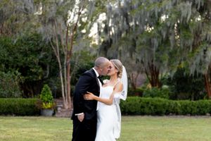 Intimate wedding moment captured in garden setting with Spanish moss trees.