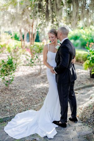 A romantic wedding moment captured under Spanish moss trees with the bride in a flowing white gown.
