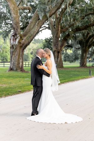 A romantic wedding moment captured under ancient oak trees draped with Spanish moss.