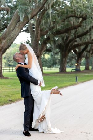 A romantic dip pose during wedding photos under majestic oak trees.