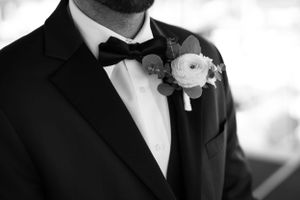 Close-up of groom's tuxedo with white floral boutonniere in black and white.
