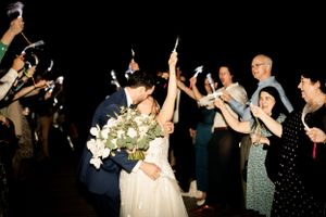 Wedding party celebrating with sparklers at night during exit celebration.