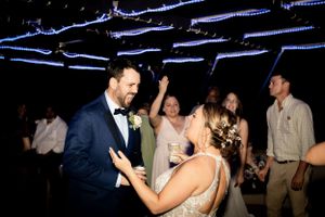 Couple dancing together under blue string lights at nighttime wedding reception.