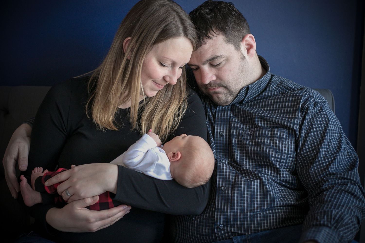 Mom and dad snuggling newborn son during their in-home newborn session in Sioux City, IA.