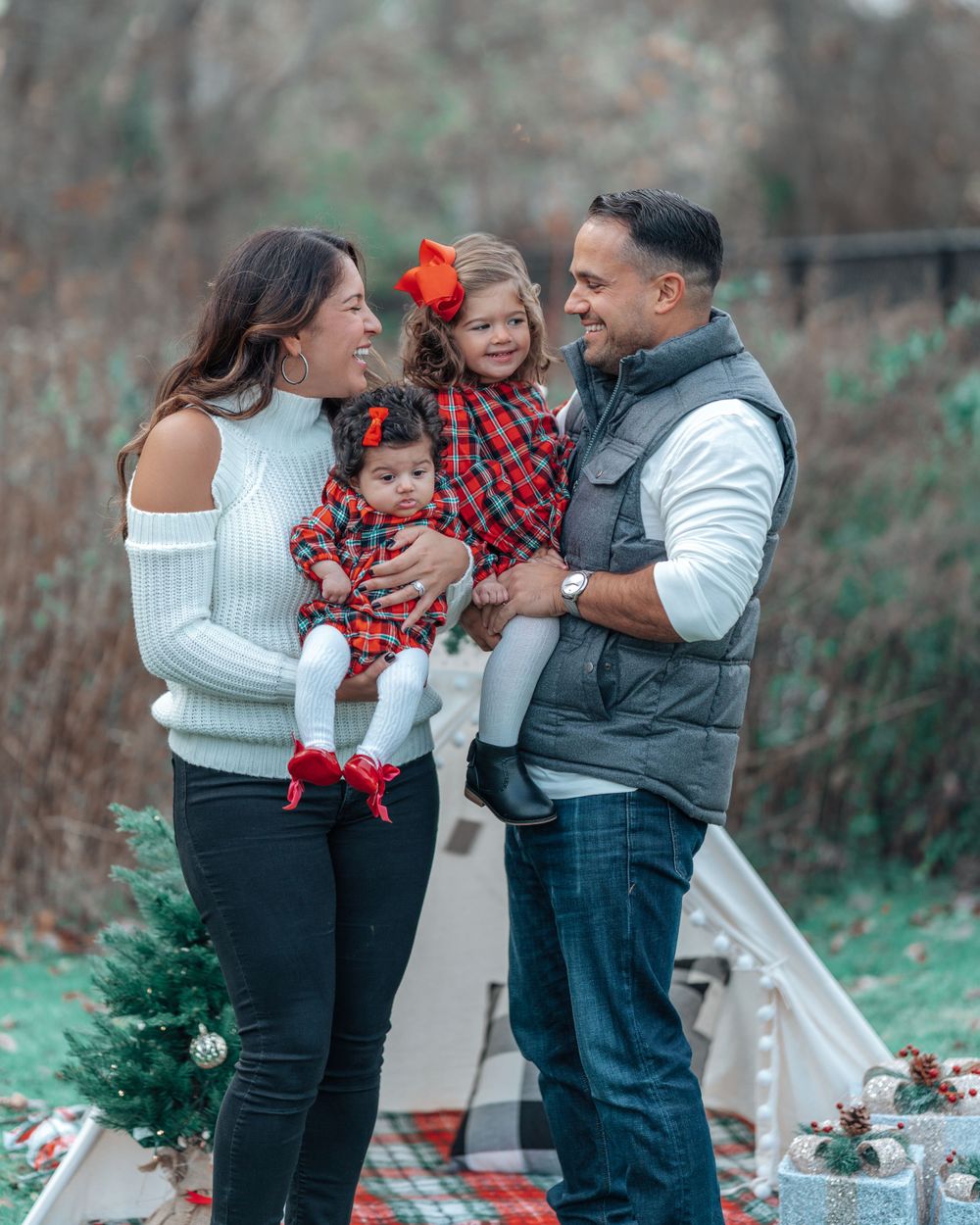 Family holiday photo with coordinated red plaid outfits and festive decorations.