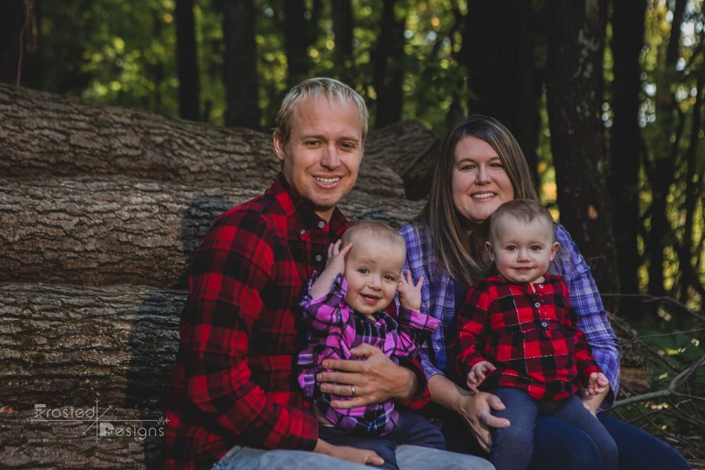 Family of 4 on wood pile for family photography session.  Mom and Dad and a set of young twins.