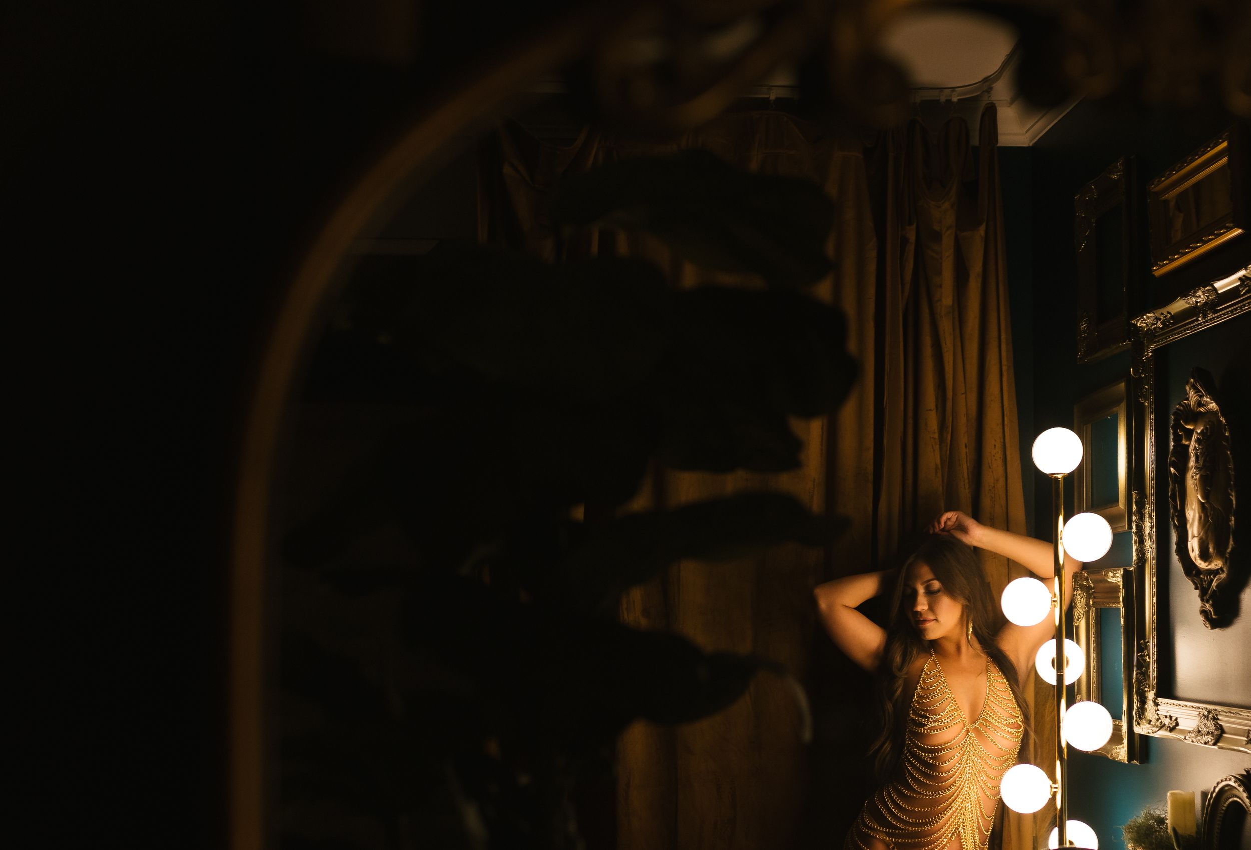 Sexy image of lady in the right bottom corner of the frame with a sexy chain outfit leaning on bubble lights. Greenville SC Boudoir