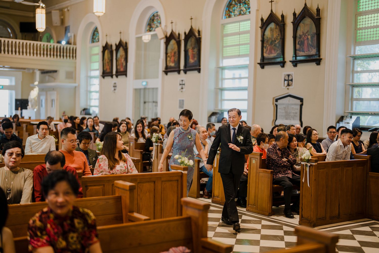 Church sanctuary with wooden pews and decorative ceiling during a wedding ceremony.