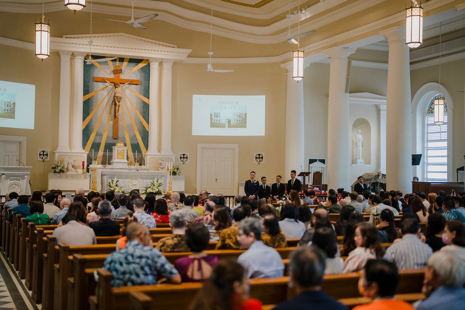 Beautiful Catholic church interior with ornate ceiling and pews filled with wedding guests.